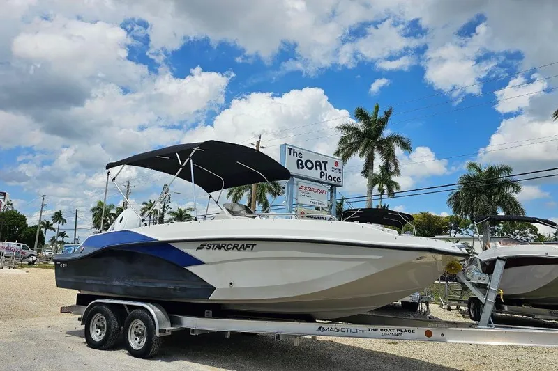 The Image of 2023 Starcraft SVX 211 OB boat on trailer at dealership under blue sky. - 0