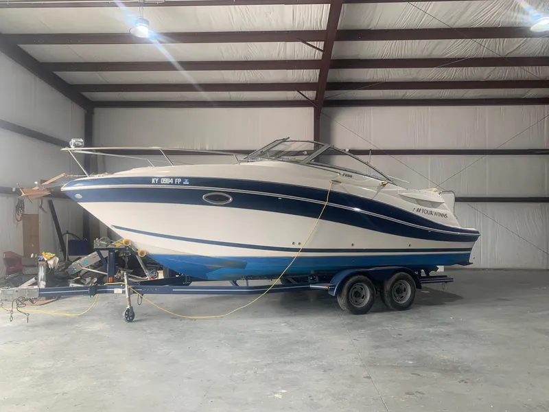 Slide: The Image of 2008 Four Winns V258 boat on trailer in a spacious indoor storage facility. - 2