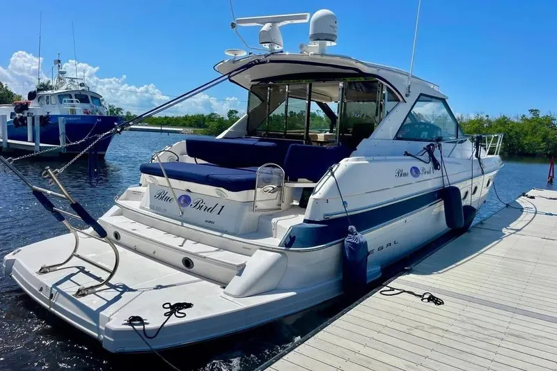 The Image of 2011 Regal 46 Sport Coupe yacht docked at marina under clear blue sky. - 1