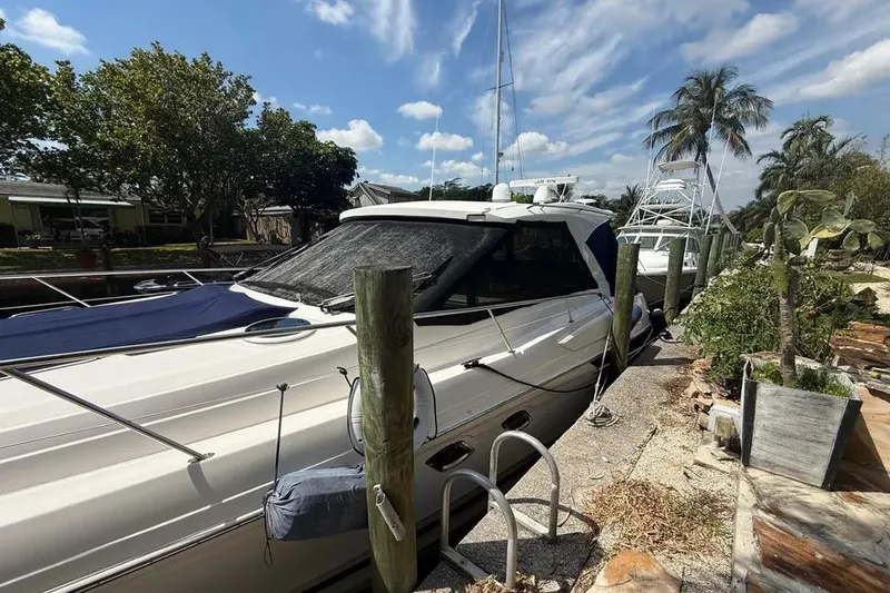 Slide: The Image of 2011 Regal 46 Sport Coupe yacht docked by palm trees under a blue sky. - 4