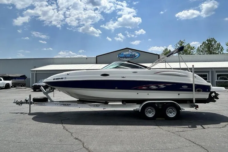 The Image of 2006 Chaparral Sunesta 274 boat on trailer at a marine center, under a blue sky. - 1
