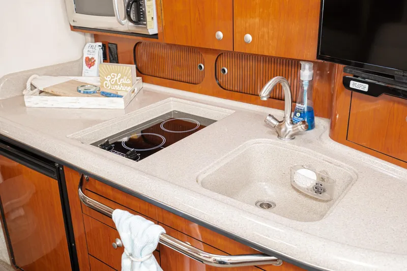 Slide: The Image of 2007 Sea Ray 340 Sundancer galley with sink, stove, and wooden cabinetry. - 43