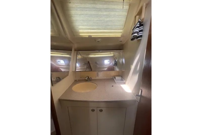 Slide: The Image of Bathroom interior of 2001 Hunter 380 yacht with sink, mirror, and striped towels. - 12