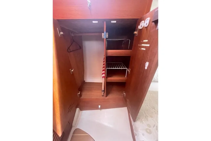 Slide: The Image of Wooden interior storage cabinet in a 2001 Hunter 380 sailboat, featuring shelves and hangers. - 17