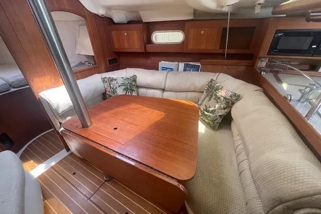 Slide: The Image of Cozy interior of 2001 Hunter 380 sailboat with wooden table and cushioned seating. - 8