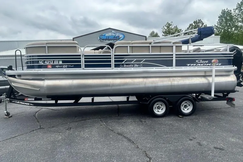 The Image of 2021 Sun Tracker SportFish 22 DLX pontoon boat on trailer at dealership. - 1
