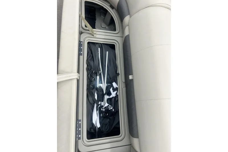 Slide: The Image of Storage compartment in 2021 Sun Tracker SportFish 22 DLX boat, containing poles and fabric. - 16