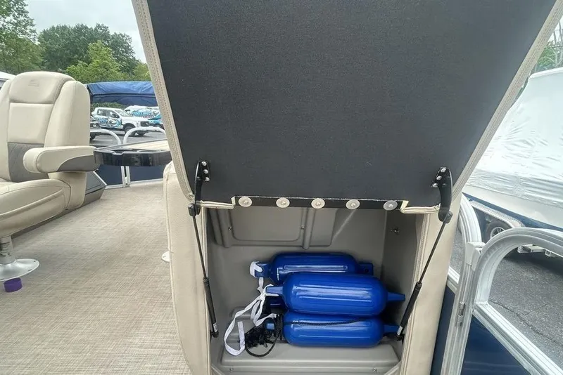 Slide: The Image of 2021 Sun Tracker SportFish 22 DLX boat storage compartment with blue fenders and beige seating. - 18