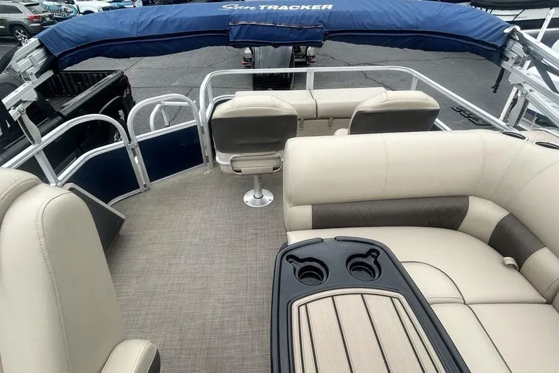 Slide: The Image of 2021 Sun Tracker SportFish 22 DLX pontoon boat interior with beige seating and cup holders. - 24