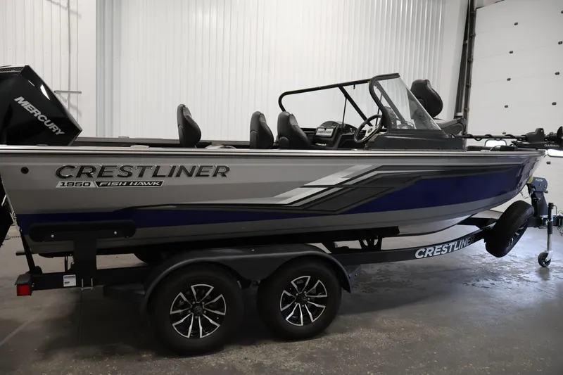 Slide: The Image of 2025 Crestliner 1950 Fish Hawk WT boat in showroom, featuring sleek design and Mercury engine. - 4