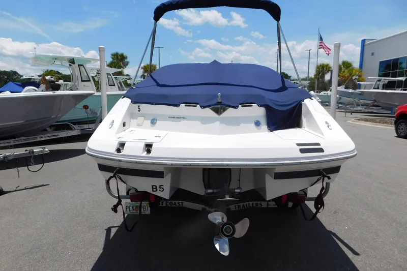 Slide: The Image of 2004 Regal 2250 LSC boat with blue cover, parked on a trailer in a marina. - 4