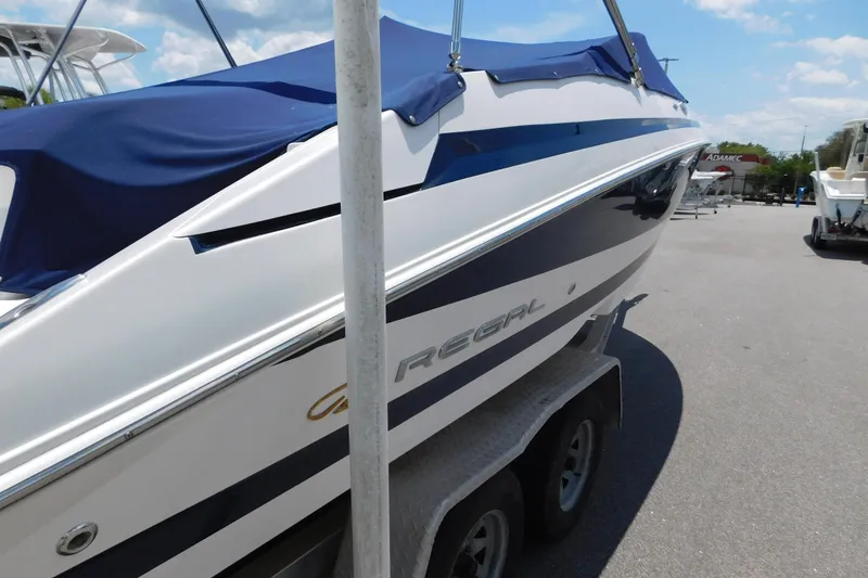 Slide: The Image of 2004 Regal 2250 LSC boat with blue cover on trailer, parked outdoors. - 8