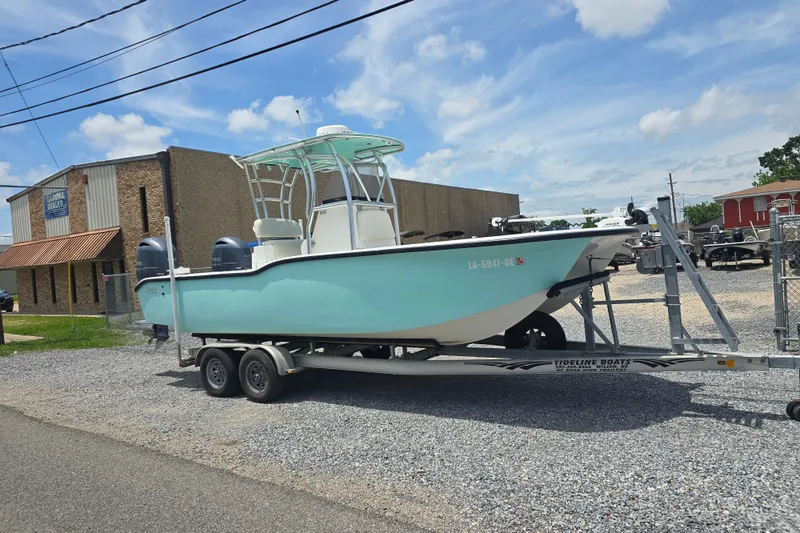 Slide: The Image of 2015 Tideline 235 boat on trailer, parked outside a building under a clear blue sky. - 2