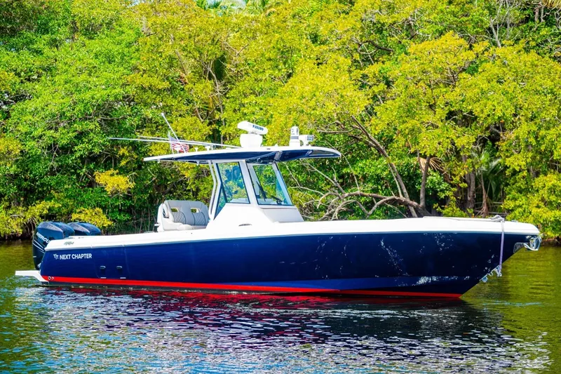 The Image of 2018 Intrepid 327 Center Console boat on water, surrounded by lush greenery. - 1