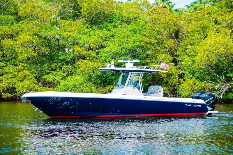 Slide: The Image of 2018 Intrepid 327 Center Console boat on calm water, surrounded by lush greenery. - 11