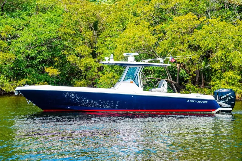 Slide: The Image of 2018 Intrepid 327 Center Console boat on water, surrounded by lush greenery. - 12