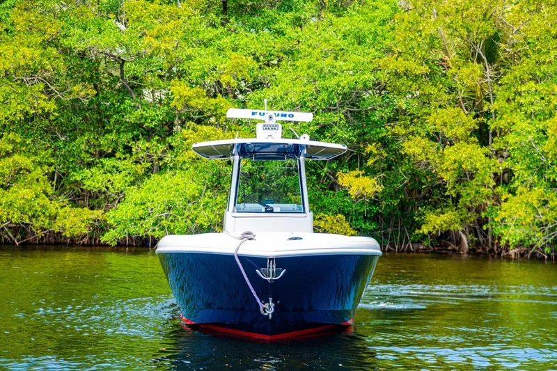 Slide: The Image of 2018 Intrepid 327 Center Console boat on calm water, surrounded by lush greenery. - 15