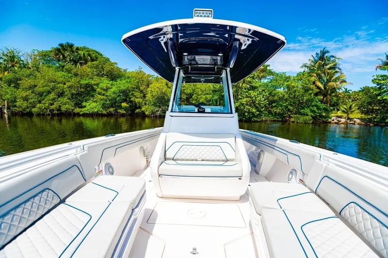 Slide: The Image of 2018 Intrepid 327 Center Console boat with luxurious seating, surrounded by lush greenery and calm waters. - 17