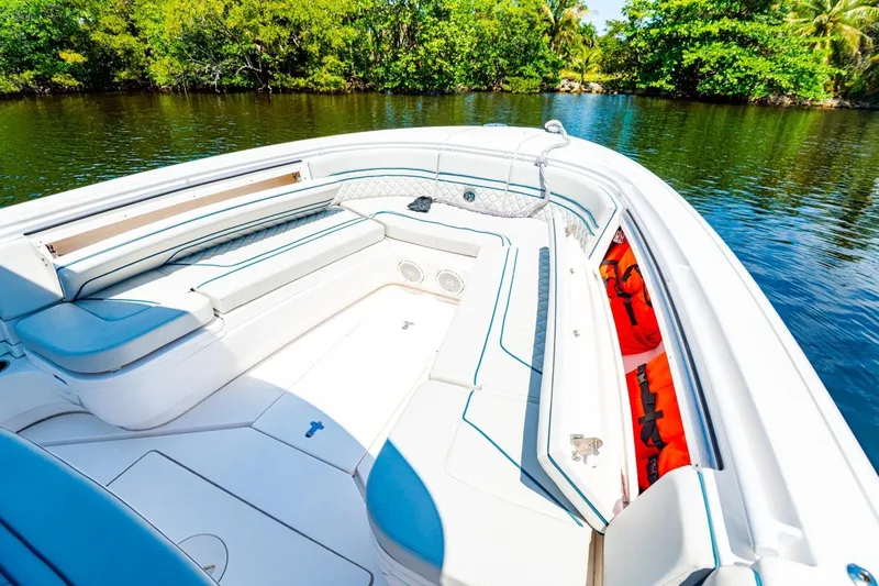 Slide: The Image of 2018 Intrepid 327 Center Console boat interior with seating, on calm water, surrounded by greenery. - 21