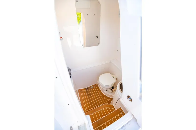 Slide: The Image of Interior of 2018 Intrepid 327 Center Console boat bathroom with wooden flooring. - 23