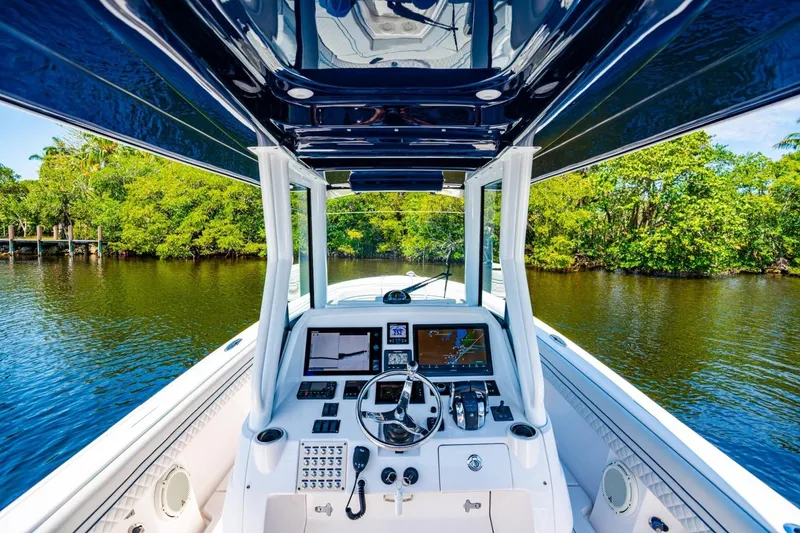 Slide: The Image of 2018 Intrepid 327 Center Console boat dashboard with navigation screens, steering wheel, and lush waterway view. - 26