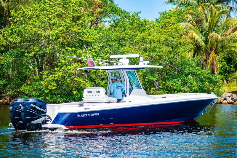 Slide: The Image of 2018 Intrepid 327 Center Console boat cruising on a scenic waterway with lush greenery. - 3