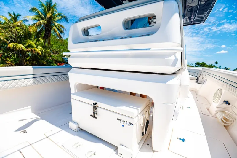 Slide: The Image of 2018 Intrepid 327 Center Console boat interior with storage compartment, tropical backdrop. - 33