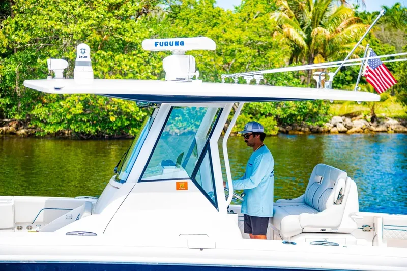 Slide: The Image of 2018 Intrepid 327 Center Console boat on water, with lush greenery background. - 42