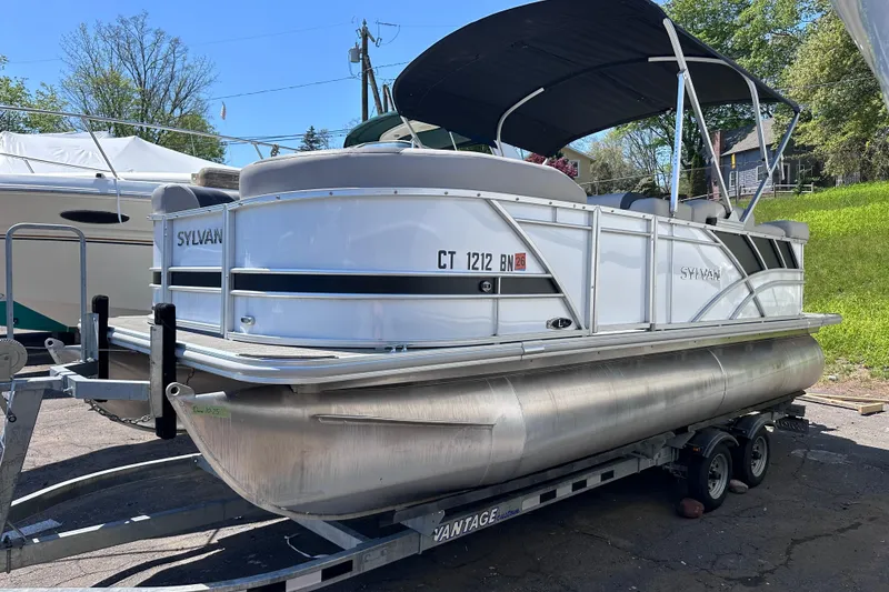 The Image of 2022 Sylvan L1 CRS pontoon boat on trailer, parked outdoors. - 0