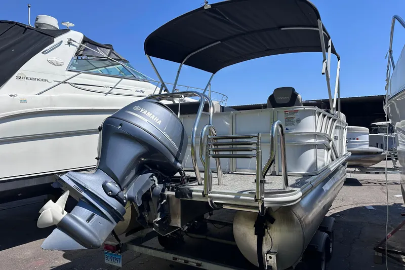 Slide: The Image of 2022 Sylvan L1 CRS pontoon boat with Yamaha outboard motor, docked under blue sky. - 3