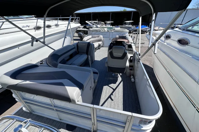 Slide: The Image of 2022 Sylvan L1 CRS pontoon boat with spacious seating and modern design in a marina setting. - 7