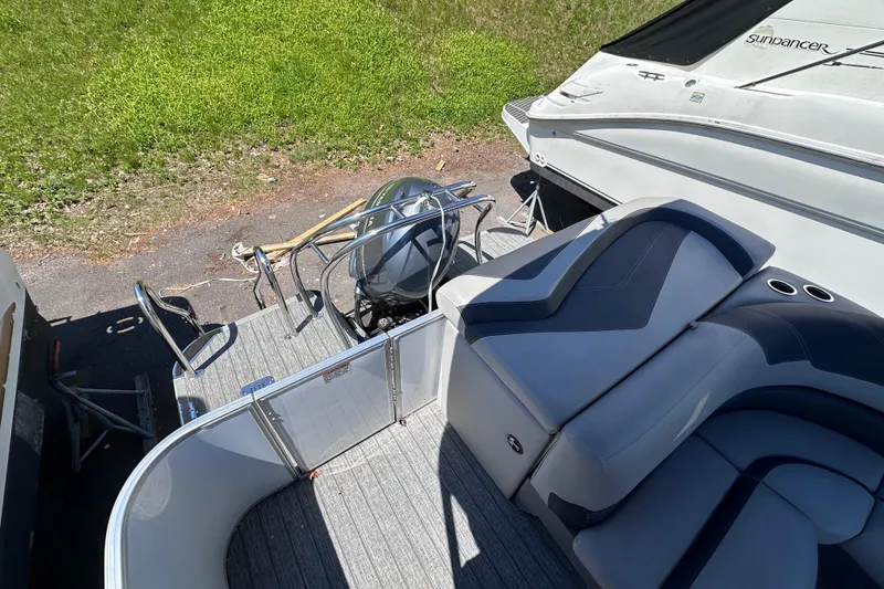 Slide: The Image of 2022 Sylvan L1 CRS boat interior with seating and motor, parked on grass. - 8