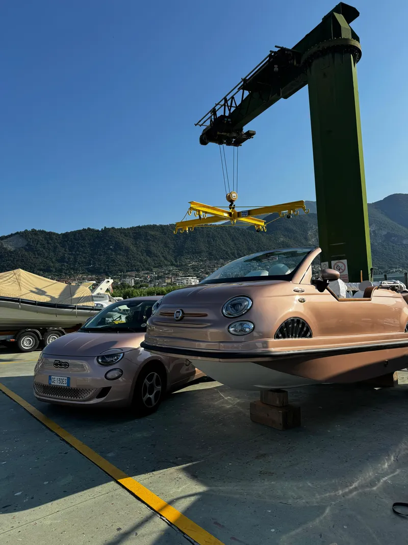 Slide: The Image of 2026 Fiat 500 Rose Gold car and boat hybrid at a dockside crane. - 2