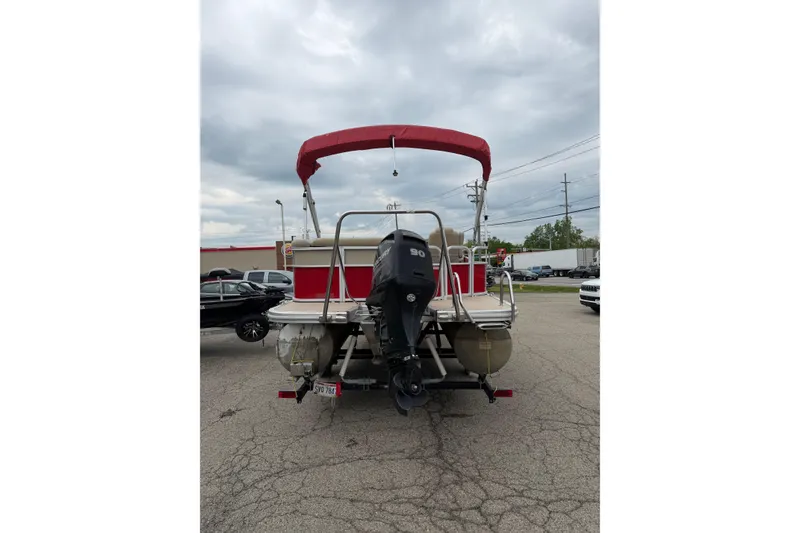 Slide: The Image of 2014 Bennington 21 SLX pontoon boat with red canopy and outboard motor, parked outdoors. - 2