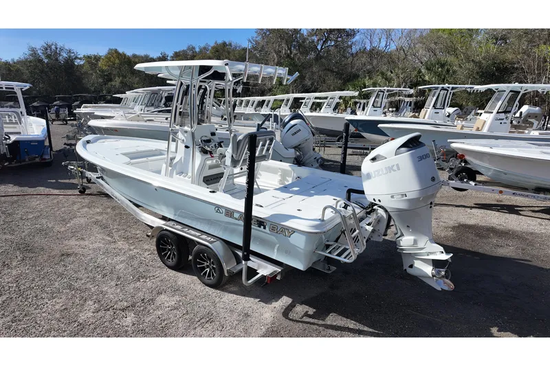 Slide: The Image of 2026 Blazer PureBay 2400 boat with Suzuki engine on trailer in marina setting. - 3