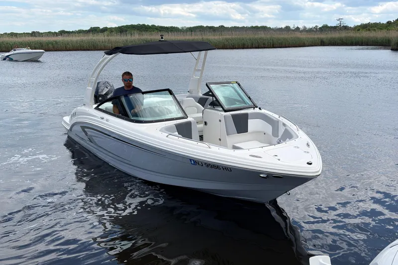 Slide: The Image of 2026 Chaparral 23 SSi OB boat on calm water with a person at the helm. - 6