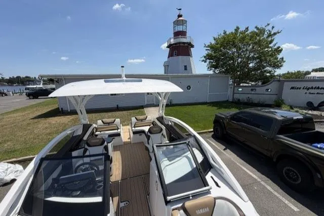 Slide: The Image of 2021 Yamaha Boats 275SD docked near a lighthouse with a truck parked nearby. - 26