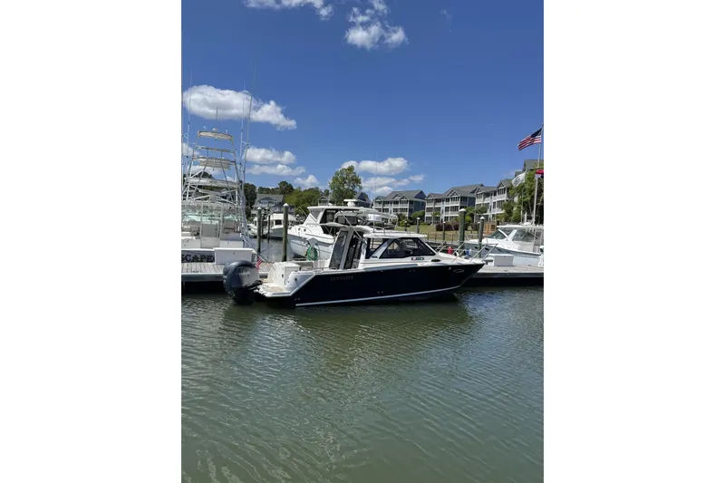 The Image of 2022 Cutwater C-248 Coupe boat docked in a marina under a clear blue sky. - 1