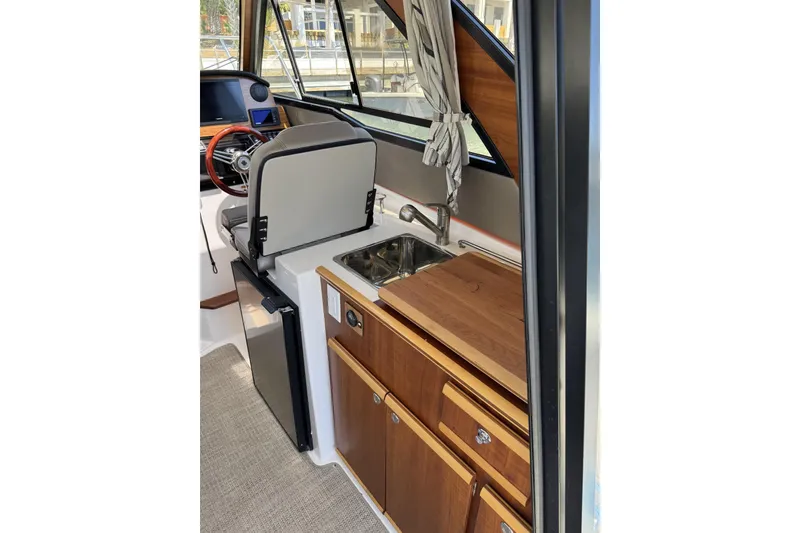 Slide: The Image of 2022 Cutwater C-248 Coupe interior with kitchenette, featuring sink, wooden cabinetry, and compact fridge. - 6