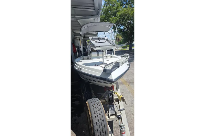 Slide: The Image of 1994 Action Craft Flatsmaster 1810 boat on trailer under shelter, ready for fishing adventures. - 2