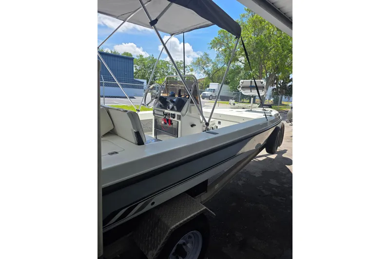 Slide: The Image of 1994 Action Craft Flatsmaster 1810 boat with canopy, parked on a trailer under a shelter. - 5