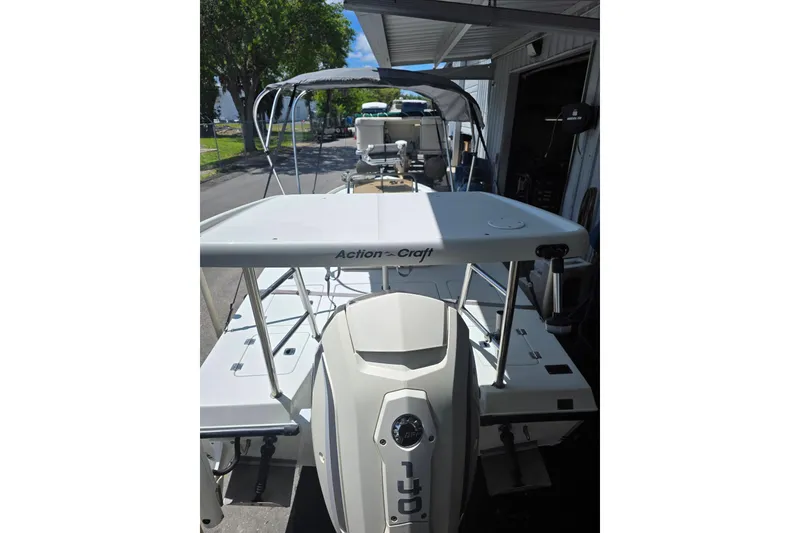 Slide: The Image of 1994 Action Craft Flatsmaster 1810 boat with canopy, parked outdoors under a shelter. - 8