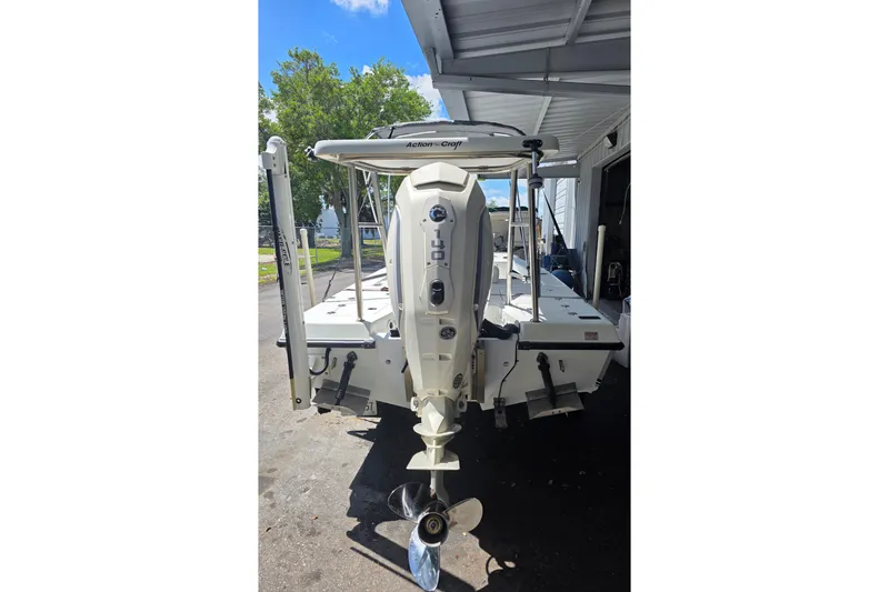 Slide: The Image of 1994 Action Craft Flatsmaster 1810 boat with outboard motor, parked under a canopy. - 9