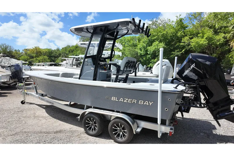 Slide: The Image of 2026 Blazer Bay 2440 boat on trailer, featuring Mercury outboard motor, parked outdoors. - 3