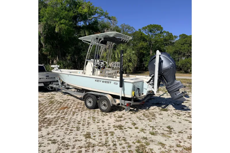 The Image of 2024 Key West 210 Bay Reef boat on trailer, parked outdoors with lush greenery. - 1