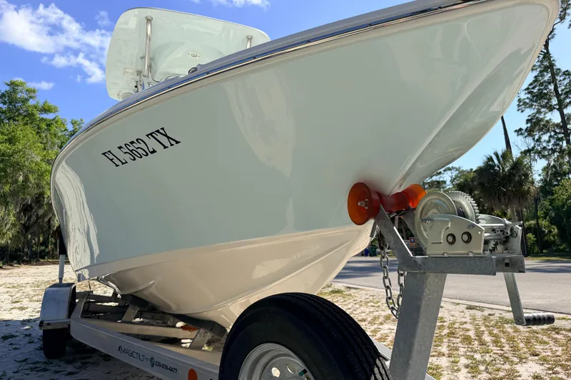 Slide: The Image of 2024 Key West 210 Bay Reef boat on trailer, parked outdoors under a clear blue sky. - 10