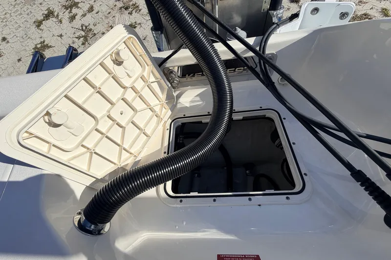 Slide: The Image of Open hatch on 2024 Key West 210 Bay Reef boat, showing interior compartment and hoses. - 114