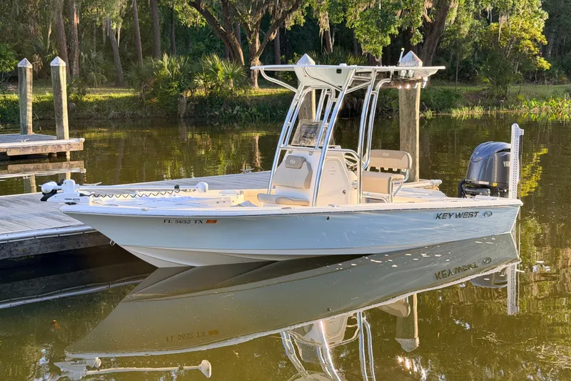 Slide: The Image of 2024 Key West 210 Bay Reef boat docked on calm water, surrounded by lush greenery. - 116