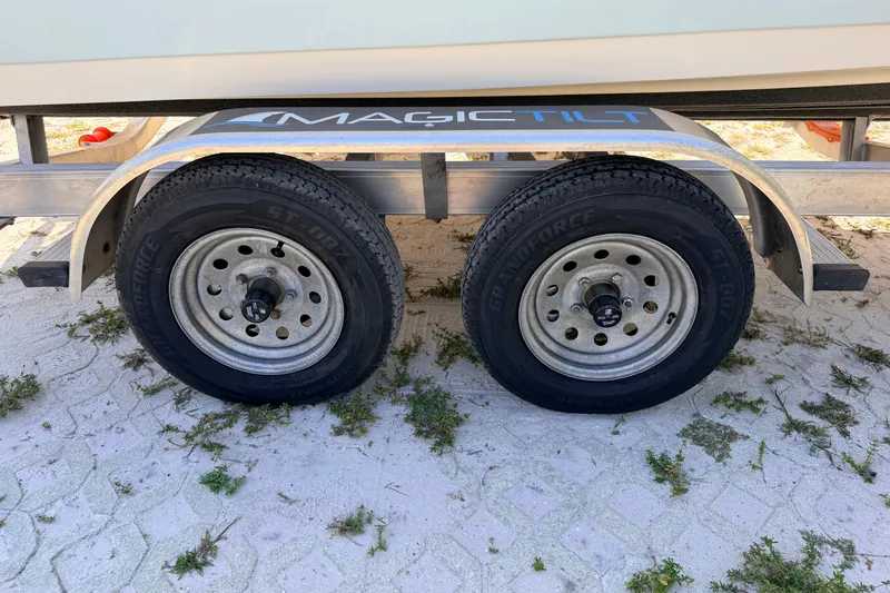 Slide: The Image of Trailer wheels of a 2024 Key West 210 Bay Reef boat on sandy ground. - 14
