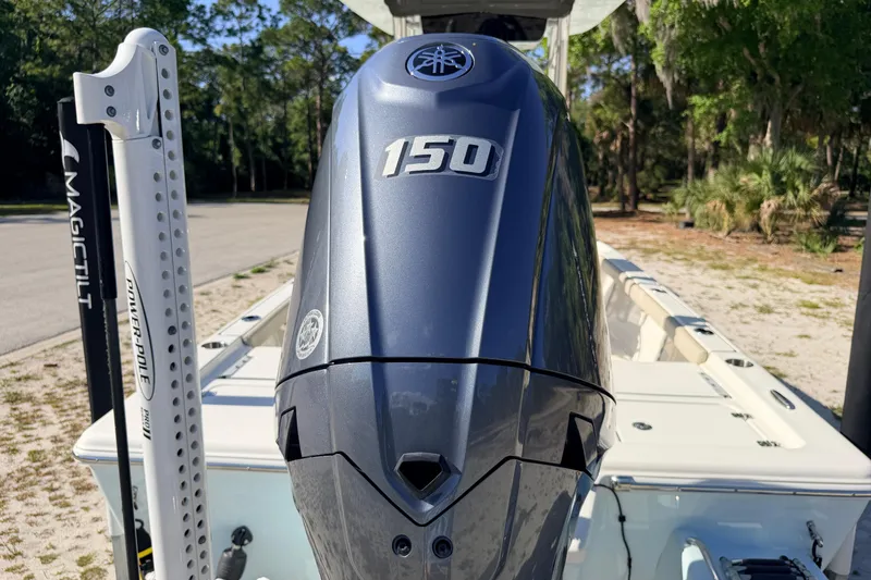 Slide: The Image of 2024 Key West 210 Bay Reef boat with Yamaha 150 outboard motor, parked outdoors. - 23